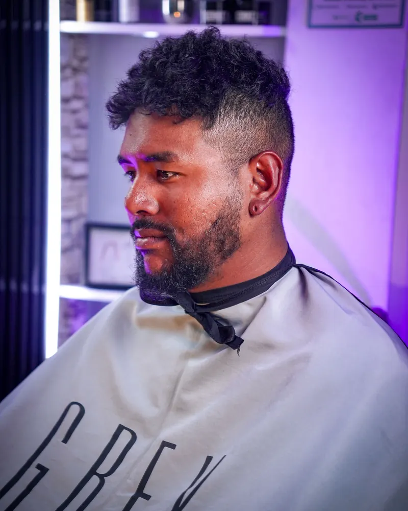 Desvanecido alto con rizos naturales arriba y barba, de perfil
