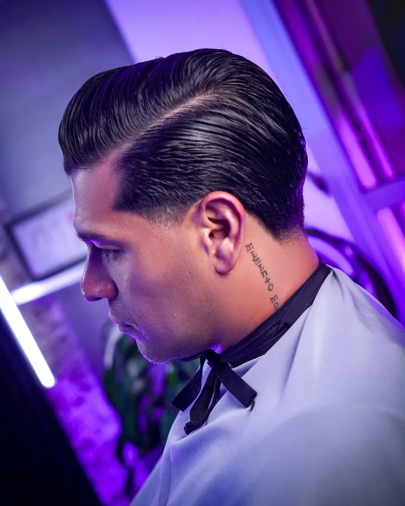 Peinado slick back clásico con raya marcada y acabado brillante